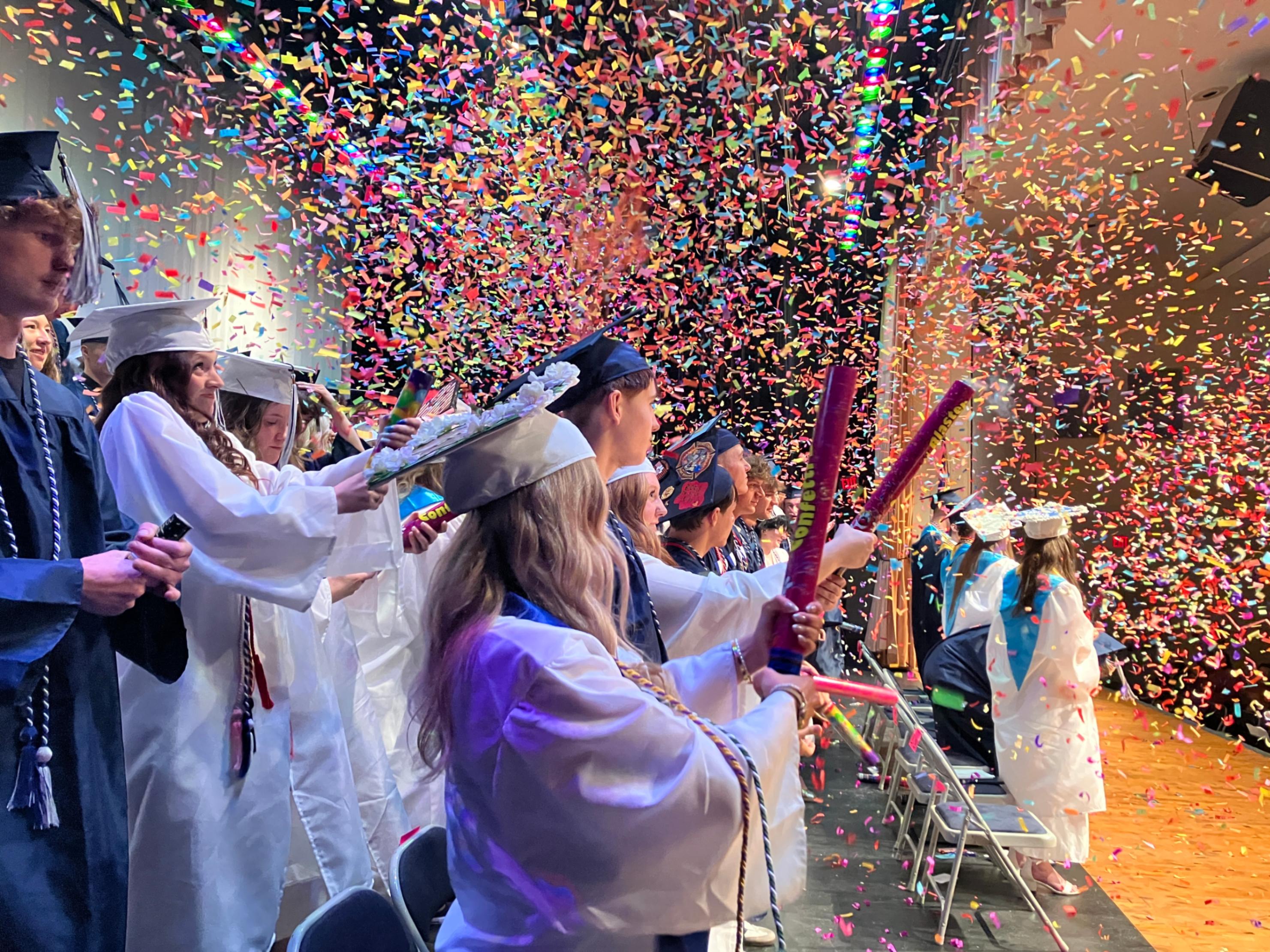 BAHS graduates pop confetti on the auditorium stage during commencement ceremonies.